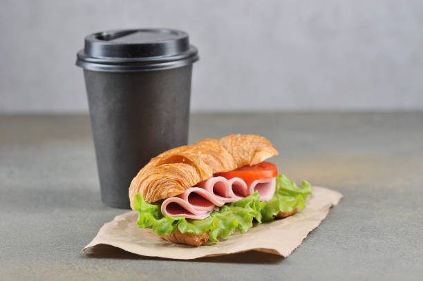 istock Coffee in a black paper cup and a ham sandwich. Free space for text. 1173133729
