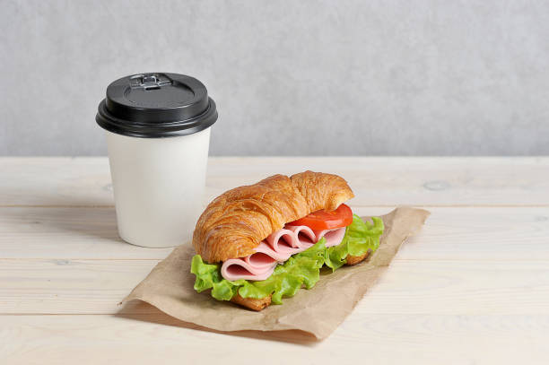istock Coffee in a white paper cup and a ham sandwich. Coffee to go concept. 1173133873