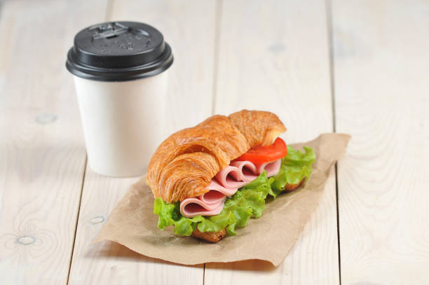 istock Coffee in a white paper cup and a ham sandwich. Free space for text. 1173133933