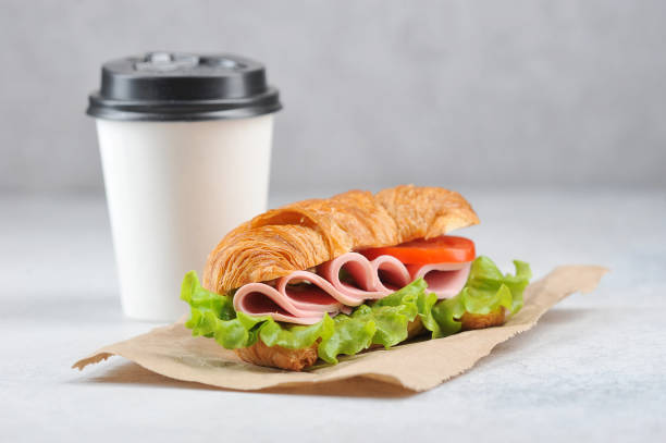 istock Coffee in a white paper cup and a ham sandwich. Coffee to go concept. Negative space. 1173134516