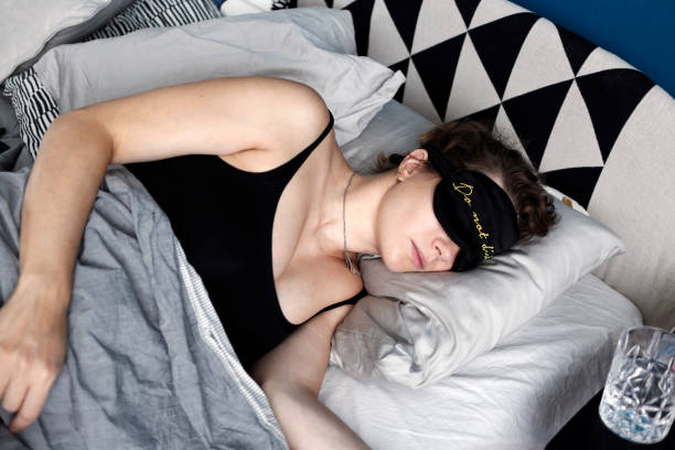 Woman sleeping in bed with her sleeping mask on stock photo
