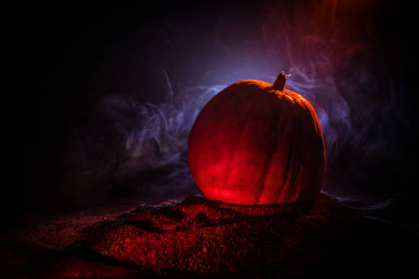 istock Halloween theme with pumpkin against smoky dark background. Empty space for text 1173139408