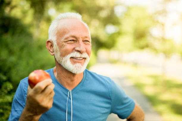 l'homme aîné sportif heureux prennent soin de sa santé. manger une pomme. - central europe photos photos et images de collection