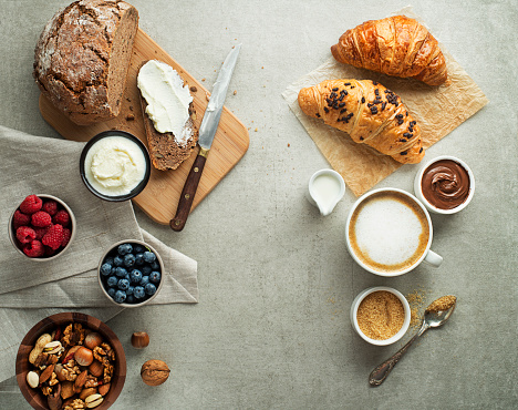 Breakfast served with croissants, coffee, bread, cream cheese and fruits. Delicious healthy breakfast.