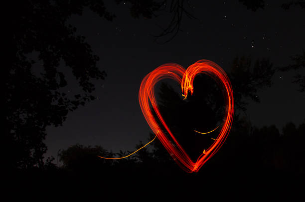 istock Heart drawn by fire on a dark background. Red heart on a black night background. Love, romantic and festival concept 1173145246