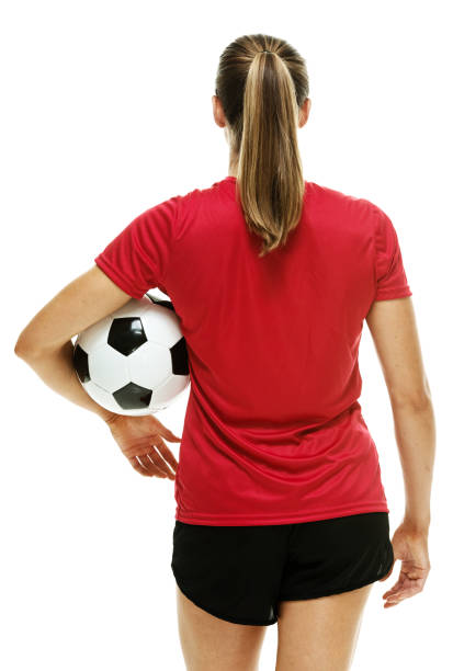 waist up / rear view / back of 20-29 years old adult beautiful brown hair / long hair caucasian female / young women soccer player / athlete / women's soccer standing in front of white background wearing soccer uniform and holding ball / soccer ball - one young woman only only young women one woman only 20 25 years imagens e fotografias de stock