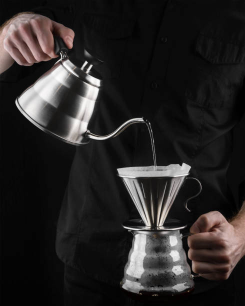 istock A barista brews coffee by an alternative method in pour over, coffee filter, glass teapot on a wooden tray on a dark background. 1173147916