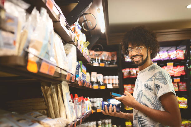 Young man shopping in a supermarket Young man buying food in a supermarket convenience store photos stock pictures, royalty-free photos & images