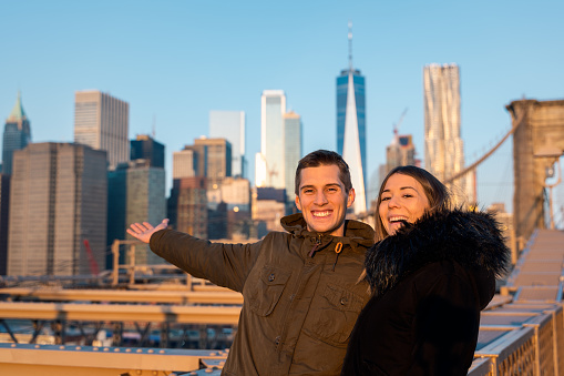 young couple on the brooklyn bridge, New York skyscrapers as background
