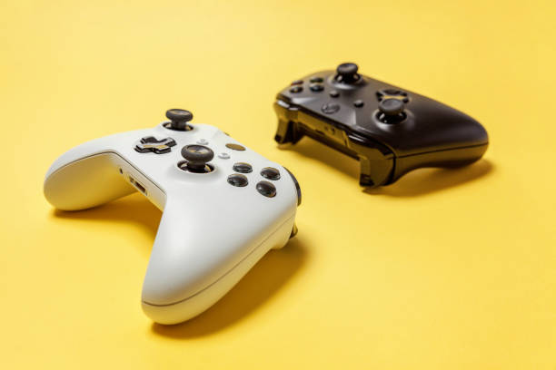 istock White and black two joystick on yellow background. Computer gaming competition videogame control confrontation concept 1173150972