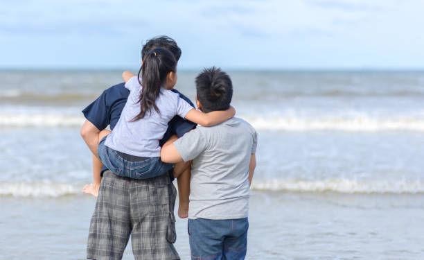 istock father and two kids walking on beach, 1173152894