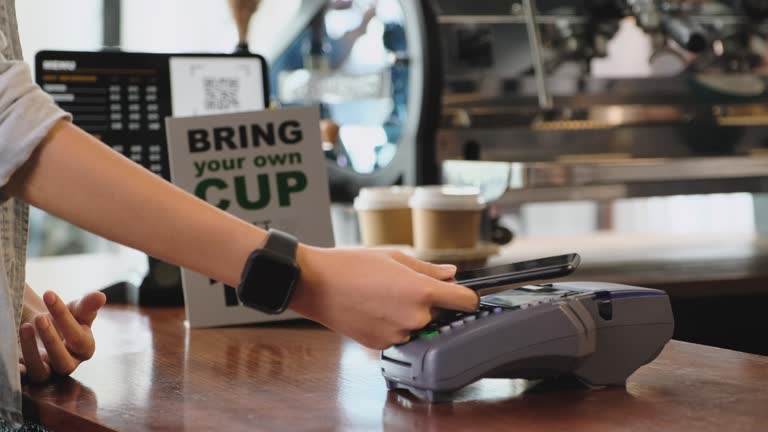 zero waste lifestyle concept.slow moiton close up hand of asian woman customer bring own cup to buy coffee and pay contactless with mobile phone to barista on counter bar at cafe