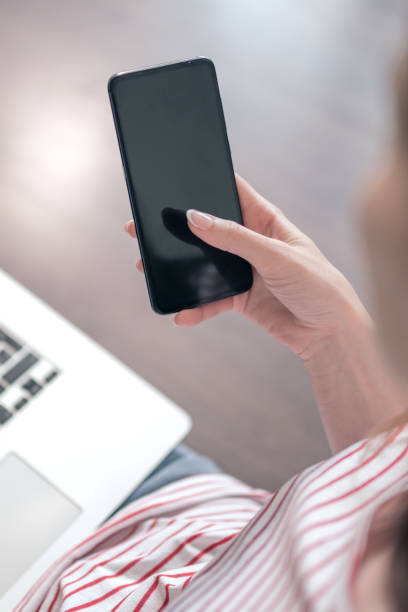 istock Woman uses smartphone and laptop at home 1173154657