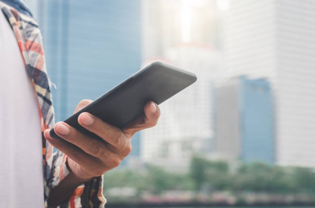 istock close up handsome man using hand typing smartphones and touch screen working search with app devices outdoor in city with sunrise and building background. 5G technology connecting the world. 1173154796