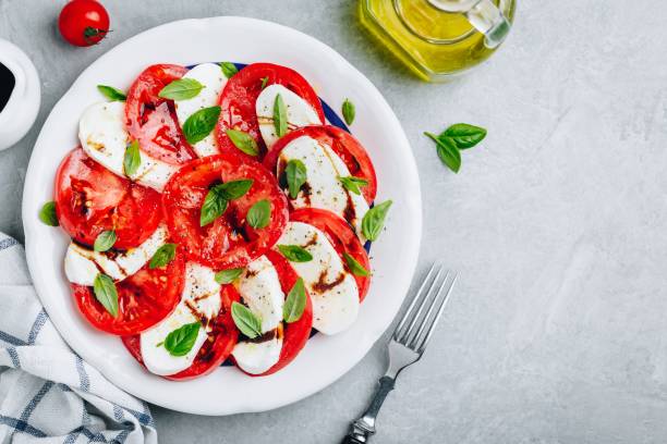 Tomato, basil, mozzarella Caprese salad with balsamic vinegar and olive oil. Tomato, basil, mozzarella Caprese salad with balsamic vinegar and olive oil. Top view, gray stone background caprese salad stock pictures, royalty-free photos & images