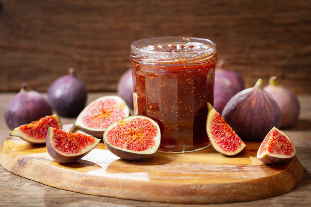 glass jar of figs jam with fresh fruits glass jar of figs jam with fresh fruits on wooden table fig photos stock pictures, royalty-free photos & images