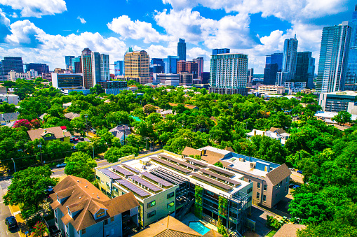 Solar Panel Community in Austin Texas a sustainable city fighting climate change with solar energy rooftop array on building surrounded by downtown skyline cityscape aerial drone view with green landscape