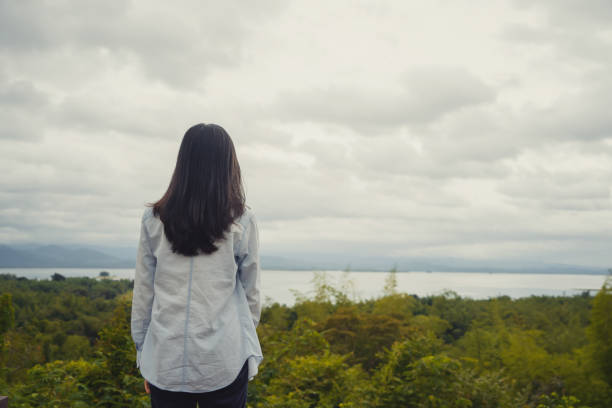 istock Lonely Asian woman thinking about problems and suffering at the tropical forest during travel trip and holidays vacation outdoors at national park, Kanchanaburi, Thailand. 1173178808