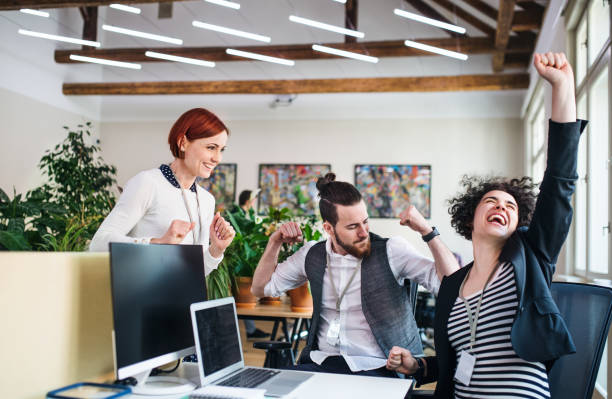 istock Group of young cheerful businesspeople using laptop in office, expressing excitement. 1173179111