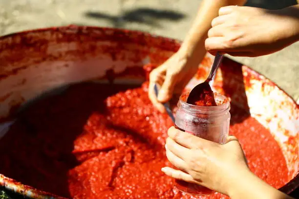Tomato paste made in the village after boiling, taken from the cauldron filling the jars moment.