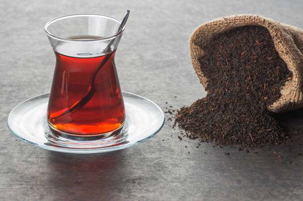 istock Glass Turkish brewed black tea with dry black tea in burlap sack on black rustic background. Turkish traditional hot drink 1173186188