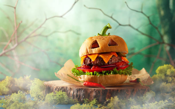 Hamburguer do partido de Halloween na forma da abóbora assustador na placa de madeira natural. - foto de acervo