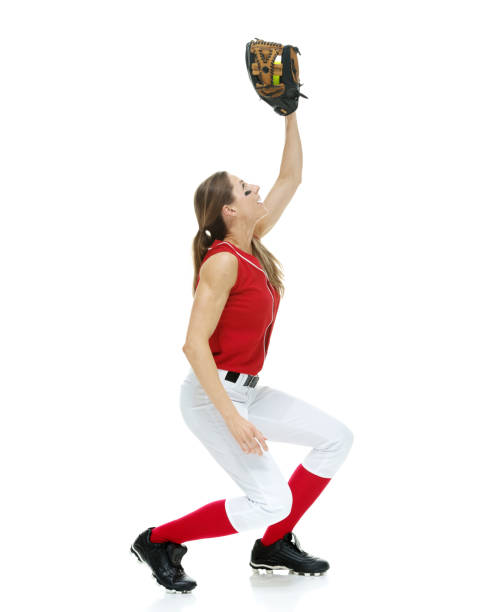 full length / side view / profile view / looking up of 20-29 years old adult beautiful brown hair / long hair caucasian female / young women softball player / athlete / softball pitcher / pitcher standing in front of white background / sport - 20 25 years profile female young adult imagens e fotografias de stock