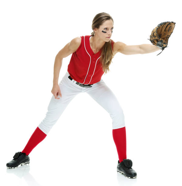 lunghezza intera / vista laterale / vista del profilo di 20-29 anni adulto bellissimi capelli castani / capelli lunghi caucasici femmina / giovane donna softball giocatore / atleta / lanciatore softball / lanciatore in piedi di fronte a sfondo bianco che s - softball adult catching beautiful foto e immagini stock