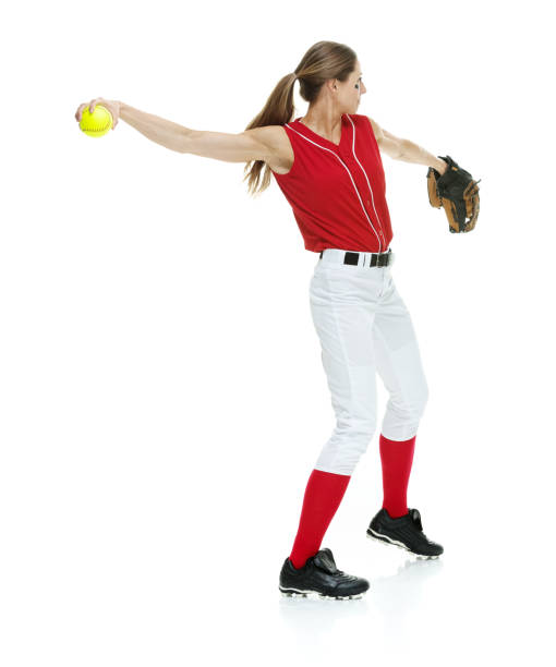 lunghezza intera / vista laterale / vista del profilo di 20-29 anni adulto bellissimi capelli castani / capelli lunghi caucasici femmina / giovane donna softball giocatore / atleta / lanciatore softball / lanciatore in piedi di fronte allo sfondo bianco e  - softball adult catching beautiful foto e immagini stock