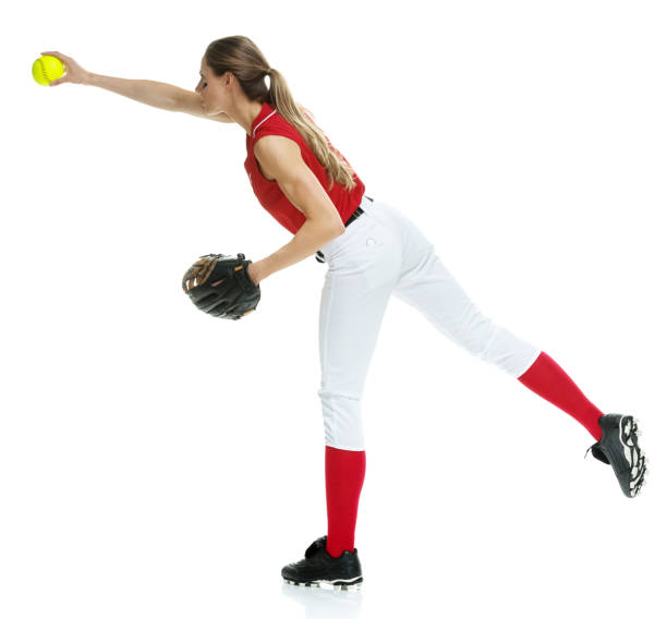 lunghezza intera / vista laterale / vista del profilo di 20-29 anni adulto bellissimi capelli castani / capelli lunghi caucasici femmina / giovane donna softball giocatore / atleta / lanciatore softball / lanciatore in piedi di fronte allo sfondo bianco e  - softball adult catching beautiful foto e immagini stock