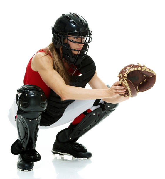 full length / side view / profile view of 20-29 years old adult beautiful brown hair / long hair caucasian female / young women baseball catcher / athlete / softball player crouching / squatting / bending in front of white background with eye black - 20 25 years profile female young adult imagens e fotografias de stock