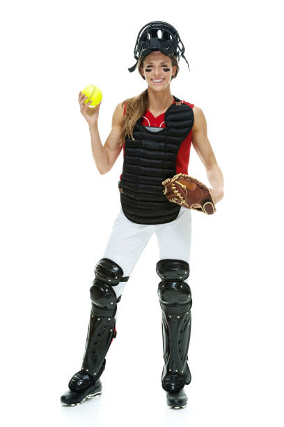 lunghezza intera / vista frontale di 20-29 anni adulto bellissimi capelli castani / capelli lunghi caucasica femmina / giovane donna baseball catcher / atleta / softball giocatore in piedi di fronte a sfondo bianco indossando guanto da baseball / maschera  - softball adult catching beautiful foto e immagini stock