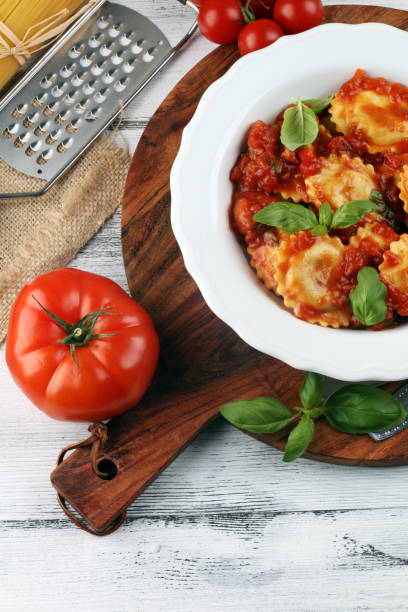 istock Ravioli with tomato sauce garnished with parmesan cheese and basil on rustic table 1173190323