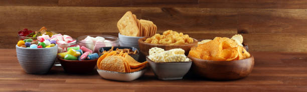 istock Salty snacks. Pretzels, chips, crackers and candy sweets on table 1173190592