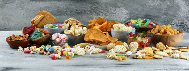 istock Salty snacks. Pretzels, chips, crackers and candy sweets on table 1173190774