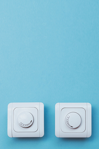 Dimmer Light Switch. Electrician switch. White rolling electricity switch on bright wall