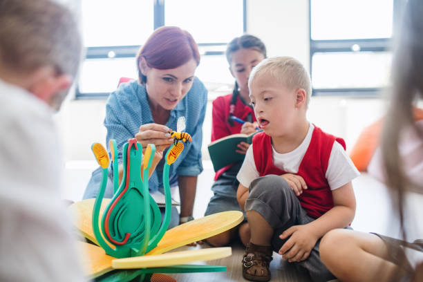 istock A group of small school kids with teacher sitting on the floor in class, learning. 1173196975