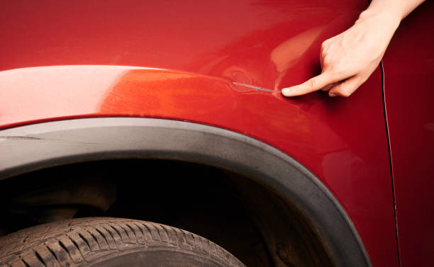 istock Hand pointing at dent on red car 1173197944