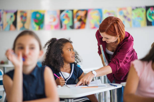 istock A teacher walking among small school children on the lesson, explaining. 1173199075