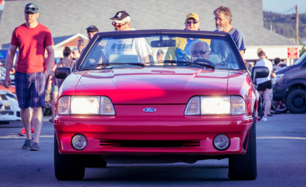 Dartmouth, Nova Scotia, Canada - August 22, 2019 : 1987 to 1993 Ford Mustang convertible at weekly summer A&W Cruise-In at Woodside ferry terminal parking lot. People walk behind the Mustang as the driver enters the parking lot.