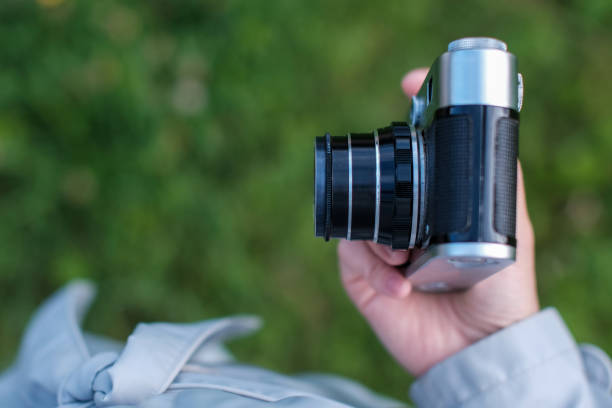 istock Female hand holding retro photo camera on background grass. Top view. 1173209233