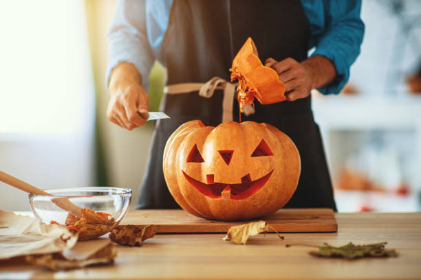hands of  man cutting pumpkin to halloween