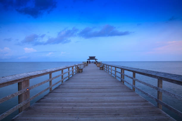 Sunrise over Naples Pier where people fish at dawn in Naples Sunrise over Naples Pier where people fish at dawn in Naples, Florida. naples beach stock pictures, royalty-free photos & images