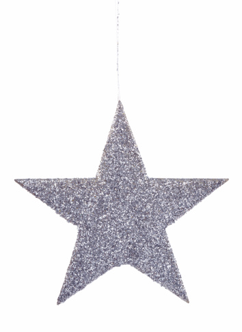 A silver star ornament covered in glitter hangs in front of a solid white background.