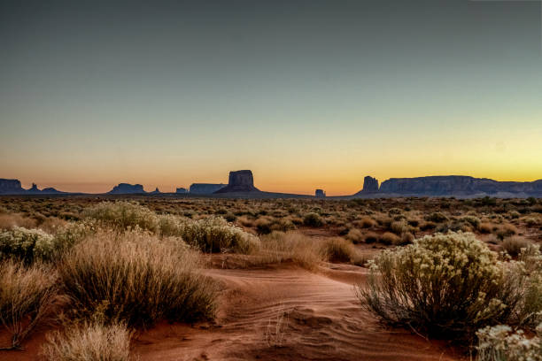 amanecer en monument valley tribal park con hermosa arena del desierto frente a los majestic mitten bluffs del parque tribal - monument valley navajo mesa monument valley tribal park fotografías e imágenes de stock