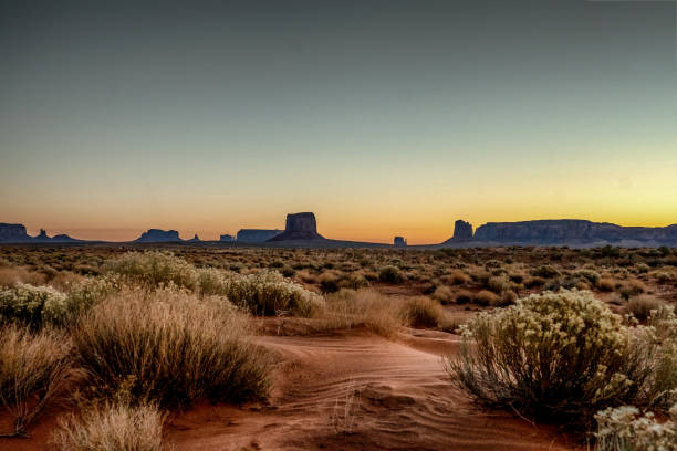 Dawn at Monument Valley Tribal Park with Beautiful Desert Sand in Front of the Majestic Mitten Bluffs of the Tribal Park Dawn at Monument Valley Tribal Park with Beautiful Desert Sand in Front of the Majestic Mitten Bluffs of the Tribal Park arizona landscape stock pictures, royalty-free photos & images