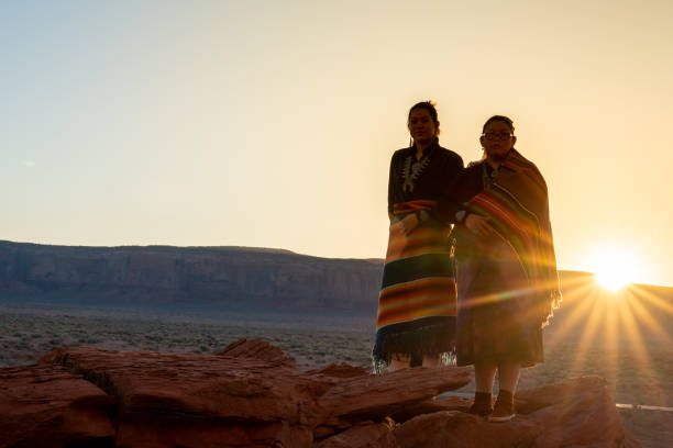 due sorelle navajo indiane native americane adolescenti in abbigliamento tradizionale che si godono il vasto deserto e il paesaggio di roccia rossa nel famoso parco tribale navajo nella monument valley arizona all'alba - cherokee foto e immagini stock