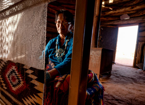 mujer navajo nativa americana en un auténtico hogan tejiendo una manta tradicional en un telar - cherokee fotografías e imágenes de stock