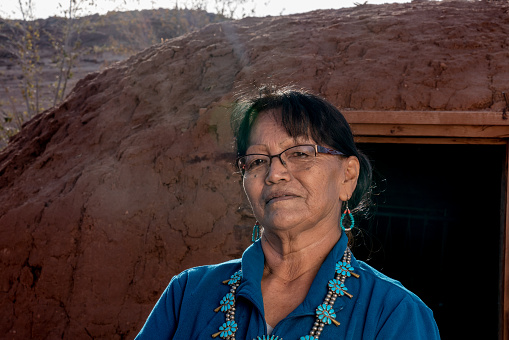 Retrato al aire libre de una mujer navajo nativa estadounidense senior frente a un Hogan tradicional en Monument Valley Arizona photo