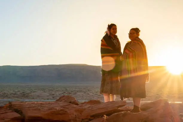 Two Traditional Navajo Native American Sisters In Monument Valley Tribal Park on a Rocky Butte Enjoying a Sunrise or Sunset stock photo
Monument Valley, Monument Valley Tribal Park, Arizona, Native American Reservation, USA